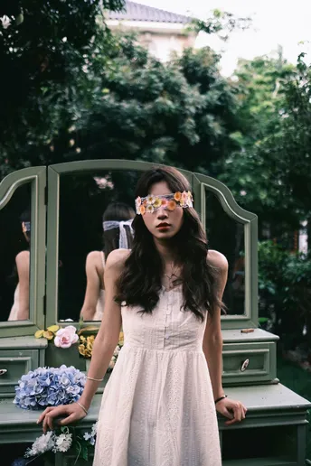 一位戴眼镜的年轻女子穿着白色连衣裙站在镜子前