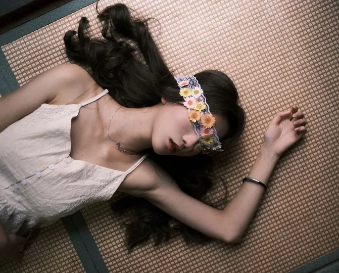 一个穿着白色连衣裙的年轻女子躺在地上 她的头靠在一个箱子上