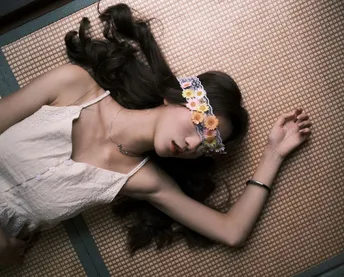 一个穿着白色连衣裙的年轻女子躺在地上 她的头靠在一个箱子上