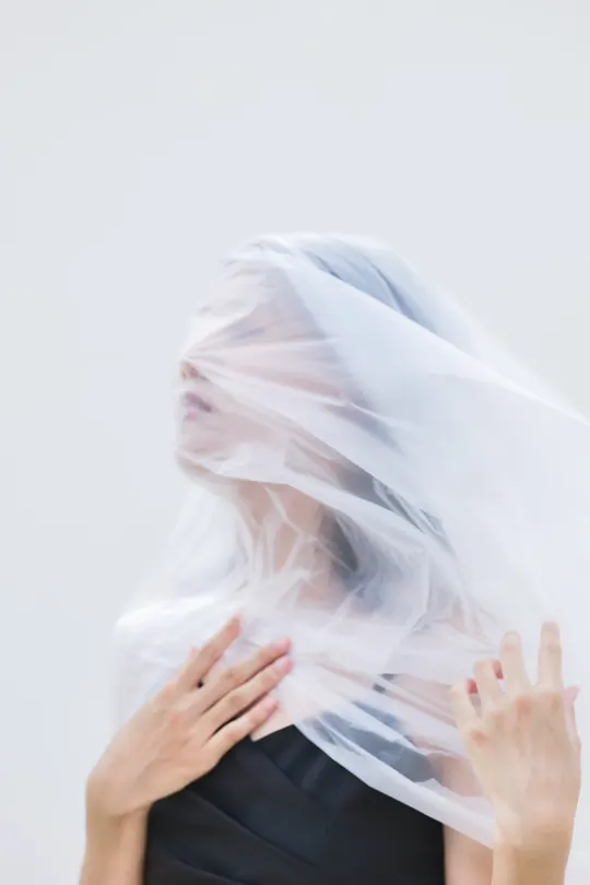 一个戴白色面纱遮住脸的女人 用双手遮住面纱