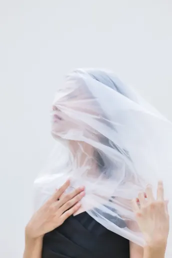 一个戴白色面纱遮住脸的女人 用双手遮住面纱