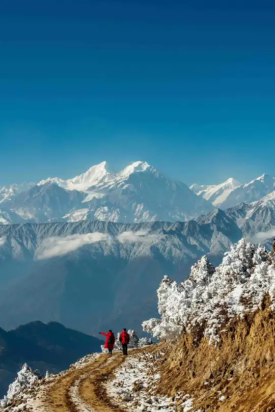 徒步旅行者沿着一条小径行走 俯瞰着白雪皑皑的山脉