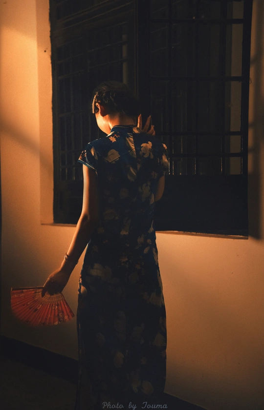 一个女人在黑暗的房间里 在窗前撑着一把红色的伞