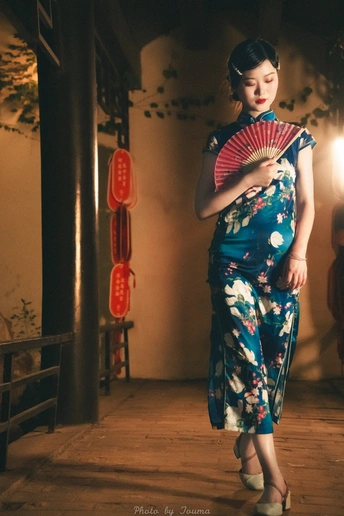 一位身穿蓝白相间和服、手持扇子的年轻女子站在房间里