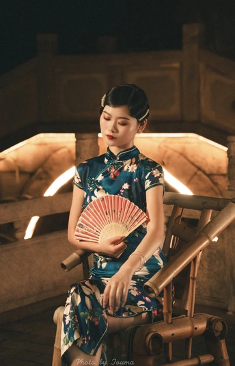 一个穿着蓝色连衣裙的年轻女子拿着一把扇子坐在椅子上