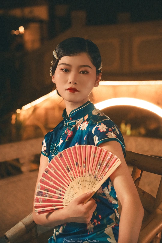 一位身穿蓝色连衣裙、手里拿着扇子和雨伞的年轻女子