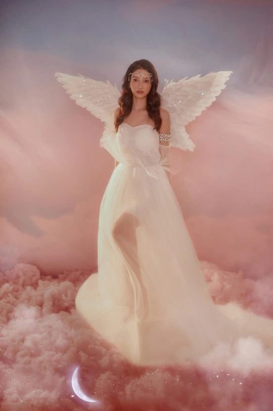 一个美丽的女人打扮成天使 长着白色的翅膀 站在粉红色的云上