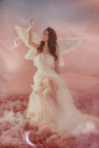 粉红色的天空中 一个穿着带翅膀的白色连衣裙的美丽女人