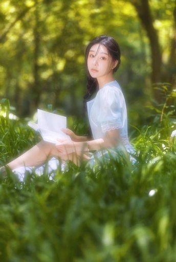 一位年轻女子坐在公园的绿草上看书