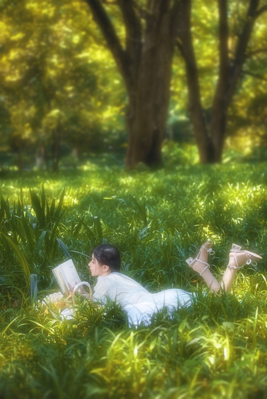 一个年轻人在给一个躺在公园绿草里的年轻女人读书