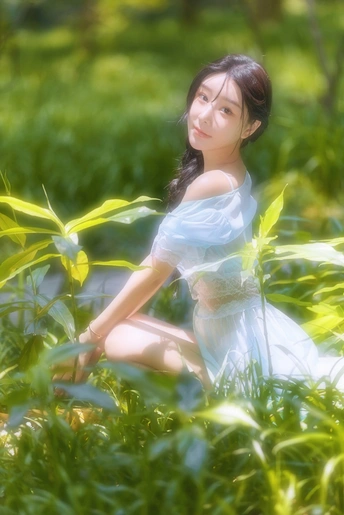 一个穿着白色连衣裙的年轻女子坐在花园的绿草中