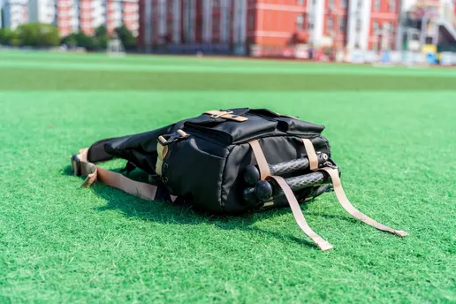一个黑色的大包躺在足球场的绿色草坪上。