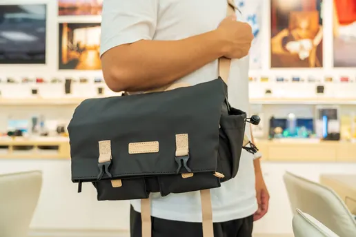 一个拿着黑色包站在商店里的男人