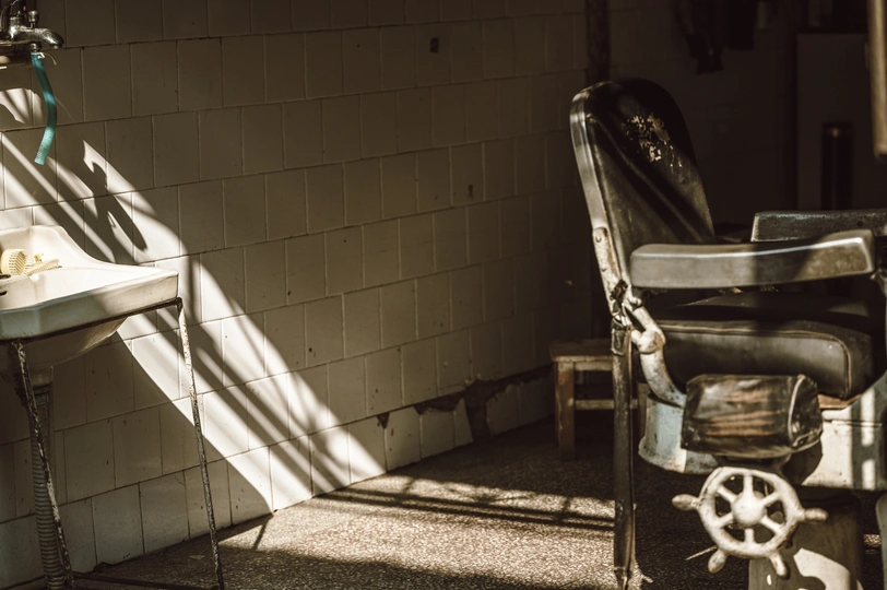 一个脏乱的浴室 旁边有一把椅子 椅子旁边有一台水槽和一扇窗户。