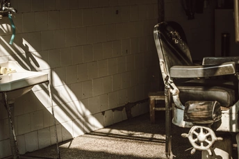 一个脏乱的浴室 旁边有一把椅子 椅子旁边有一台水槽和一扇窗户。