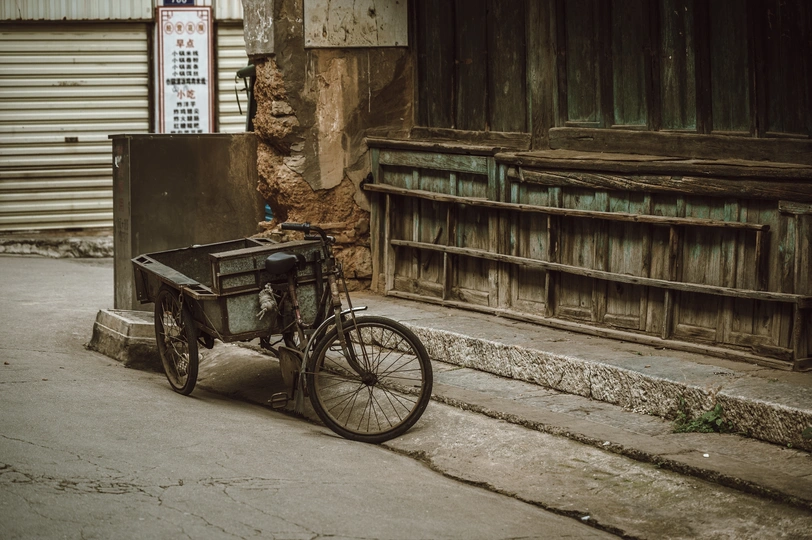 一条旧自行车停在一条小巷旁边一座旧建筑旁边