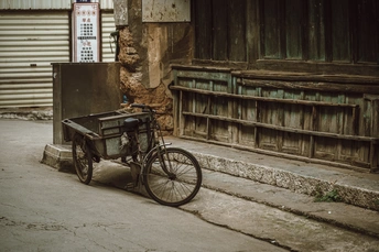 一条旧自行车停在一条小巷旁边一座旧建筑旁边