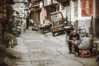 一个老人坐在一条狭窄的巷子里