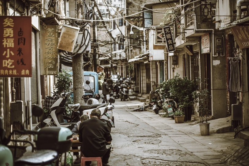 一条狭窄的老城区街道 有人们在滑板和摩托车上。