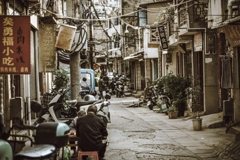 一条狭窄的老城区街道 有人们在滑板和摩托车上。