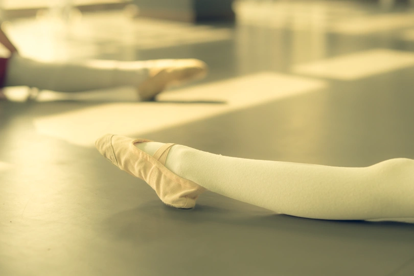 白桌子上的一位芭蕾舞女演员的腿和手臂