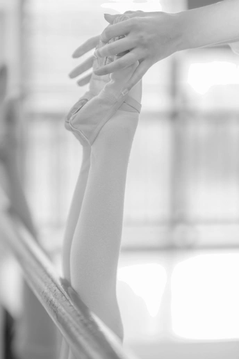 一位芭蕾舞女演员站在栏杆上 将手伸到她的手腕处。