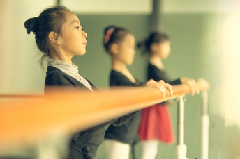 一些年轻的舞者在镜子前站立 小女孩看着他们。