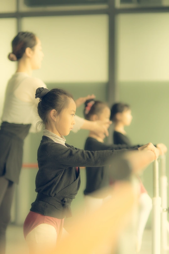 一个小女孩站在其他年轻舞者面前的镜子前