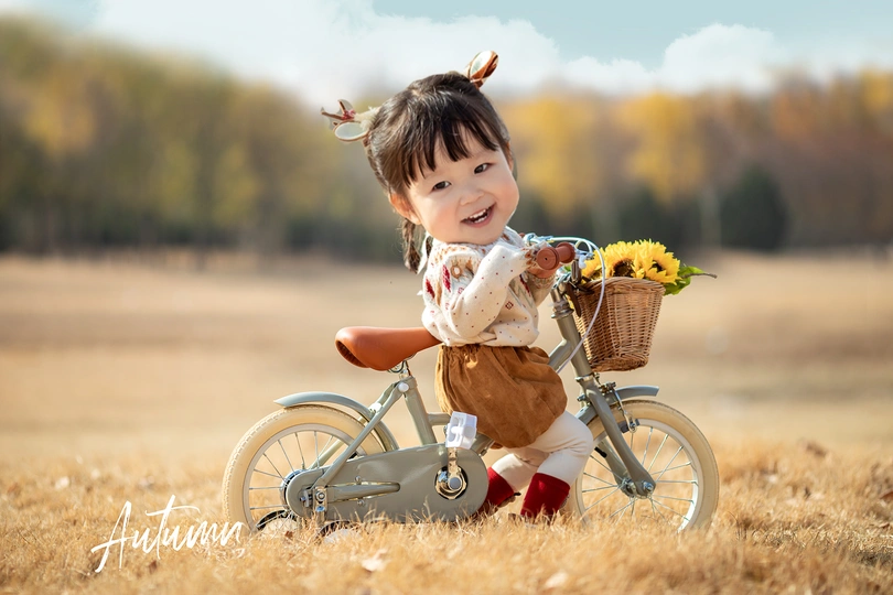 一个小女孩骑着一辆小自行车 篮子里装满了花。