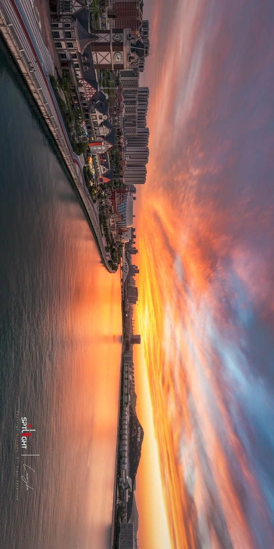 夕阳下的大海、沙滩、城市和建筑物的照片