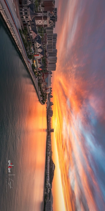 夕阳下的大海、沙滩、城市和建筑物的照片