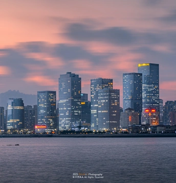 夕阳下或黄昏时的一座城市 有摩天大楼和其他建筑沿着河流。