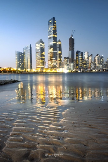 夜晚的城市 摩天大楼在水中的倒影 退潮时海滩上的沙子