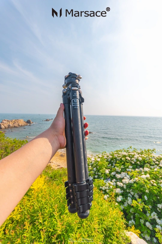 手持相机在三脚架上 背景是海洋和沙滩