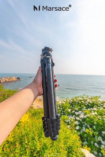 手持相机在三脚架上 背景是海洋和沙滩