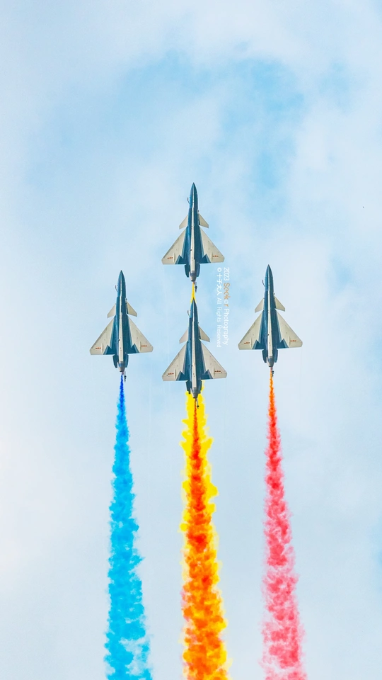 彩色的喷气机在蓝色的天空中飞过 喷出彩色烟雾。