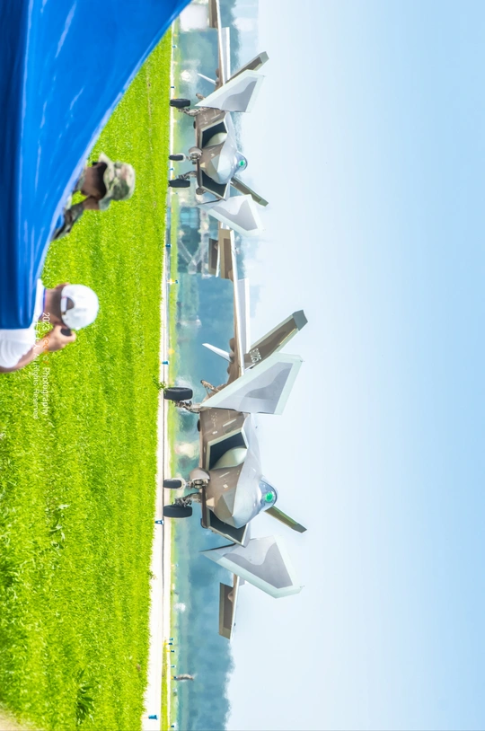 站在茂密绿色草地上 顶着一把蓝色雨伞的男子