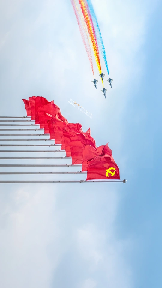 蓝天上飞行的飞机群 前景中有一面红旗