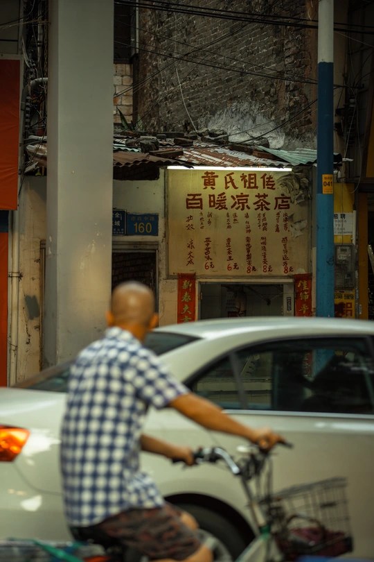 一个人骑自行车在白色汽车旁边的一条街道上
