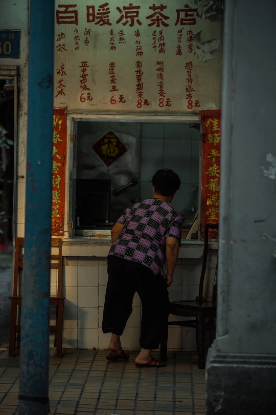 一个人坐在餐厅前面的一个小桌子旁