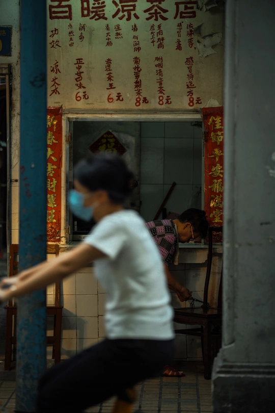 一名戴口罩的女人跑过一座人们正在玩耍的建筑物。