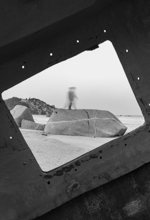 一张黑白照片 一个人在沙滩附近靠近一块大岩石