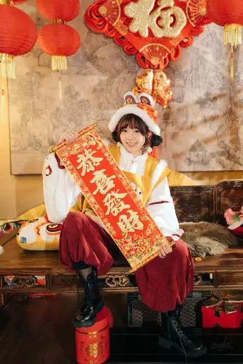一个穿着中国服装的年轻男孩坐在长凳上 小女孩拿着一个红盒子。