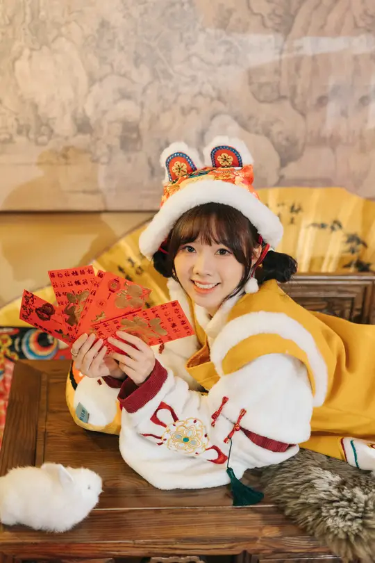 一个穿着服装的年轻女孩坐在桌子旁 一位女士拿着一张卡片。