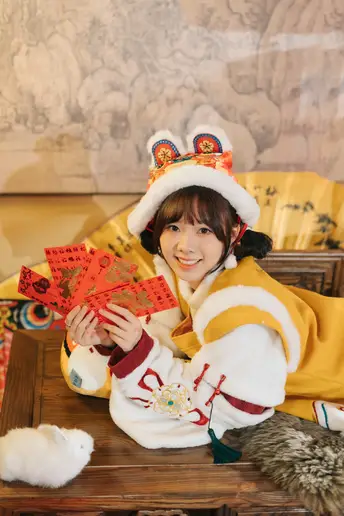 一个穿着服装的年轻女孩坐在桌子旁 一位女士拿着一张卡片。