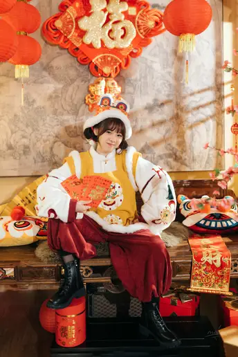 一个穿着传统服装的年轻男孩或女孩坐在挂有红灯笼的中国风格房间里。