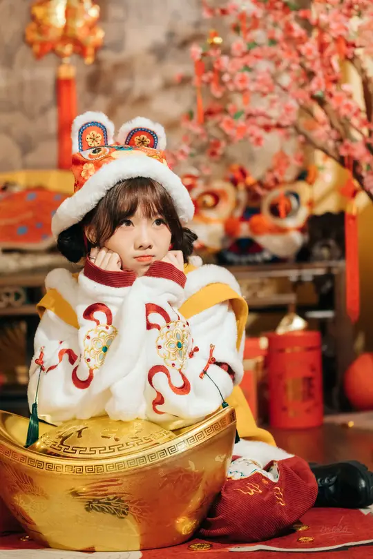 一个小女孩穿着传统服装坐在金碗里