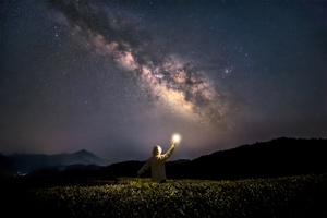 一个站在山上的男子手持电筒 凝视着夜空中的星星。