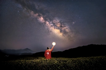 夜晚天空中星星照亮了一个拿着灯笼的人