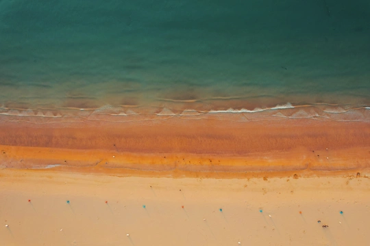 一片带有翡翠般蓝绿色水波的海滩的 aerial view
